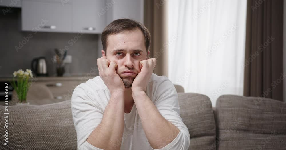 Displeased man covering ears on sofa Displeased man covering ears on sofa