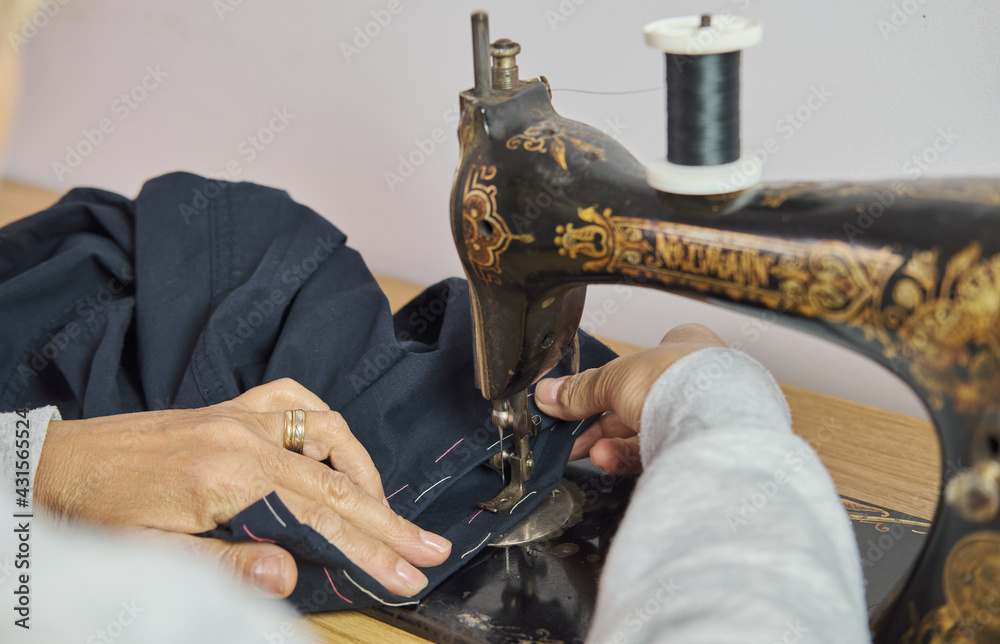 Close-up view of sewing process. Female hands stitching with a vintage sewing machine. Selective focus.