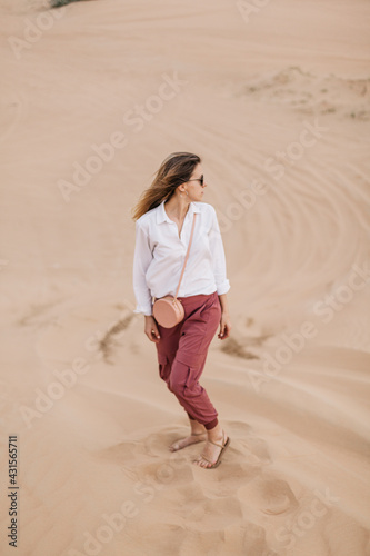 Beautiful stylish girl in the desert turning back. Best things to do in dubai.  © Stella