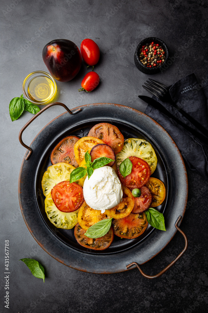 Delicious caprese salad with ripe colorful tomatoes and mozzarella cheese with fresh basil leaves. Italian food, top view