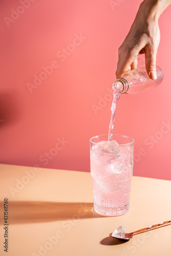 Summer refreshment pink drink with ice. Light pink rose cocktail on a pink background with bright shadows