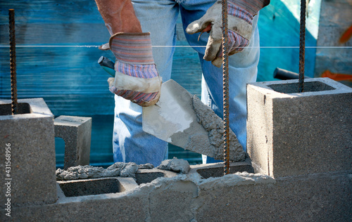 Construction site: building wall of concrete block.
Mason in laying concrete blocks
