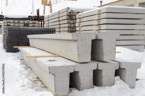 Warehouse for reinforced concrete products in winter. Reinforced concrete foundation beams for building construction.