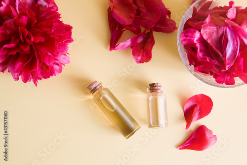 Natural cosmetics and spa concept. Bottles with essence and piones petals flat lay on a biege background