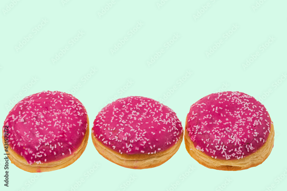View of pink donuts sprinkled with white glaze isolated on green background. Food and drink concept. View of pink donuts sprinkled with white glaze isolated on green background. Food and drink concept.