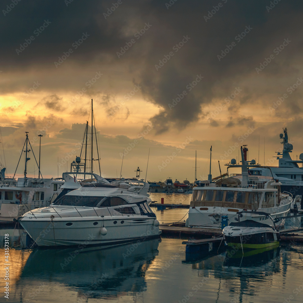 White yachts and boats in the sea harbor of the Russian resort on the Black Sea against the backdrop of a beautiful sunset sky