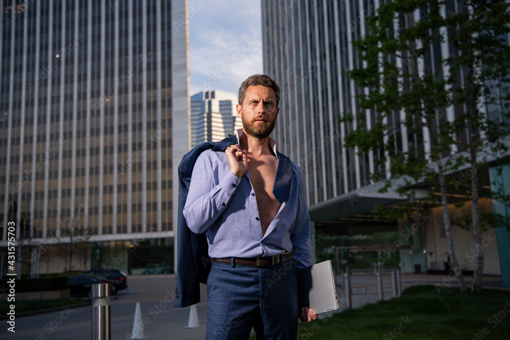 Portrait of ceo near modern office in suit. Confident sexy businessman looking away while standing outdoors with cityscape. Handsome buisness man with jacket over shoulder. Portrait of ceo near modern office in suit. Confident sexy businessman looking away while standing outdoors with cityscape. Handsome buisness man with jacket over shoulder.