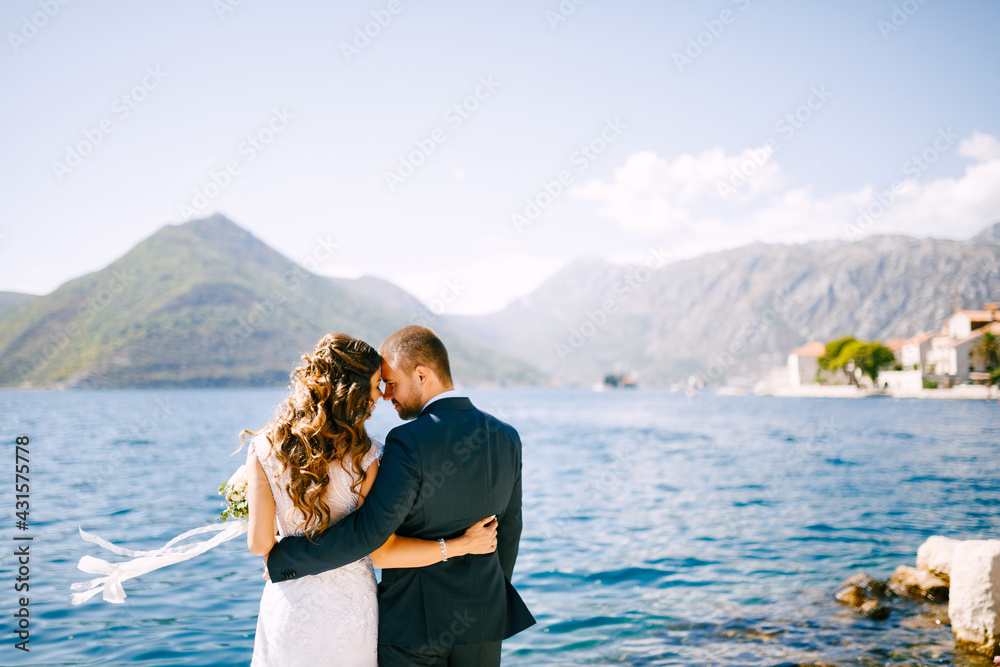 Happy smiling bride and groom embracing on the background of a beautiful mountain landscape on a sunny day.