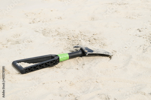 View of a black shovel on a sandy beach