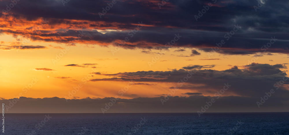An evening cloudscape panorama with vivid colors in the sky and dark clouds.
