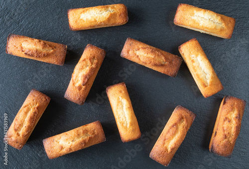 Set of traditional French food - pastries for morning coffee or tea - financier cake on a black background, top view