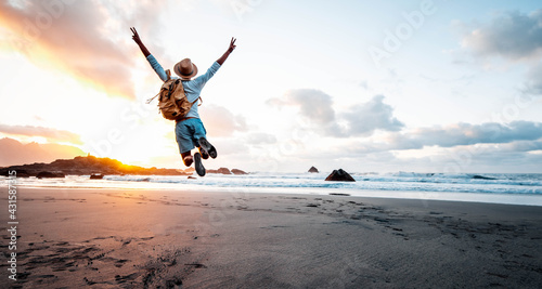 Fotografija Happy man with backpack jumping over the beach at sunset - Hiker enjoying freedo