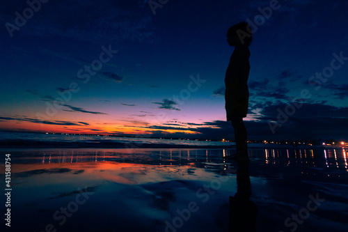 Silhueta de uma criança olhando pro horizonte na praia de Serrambi durante anoitecer.