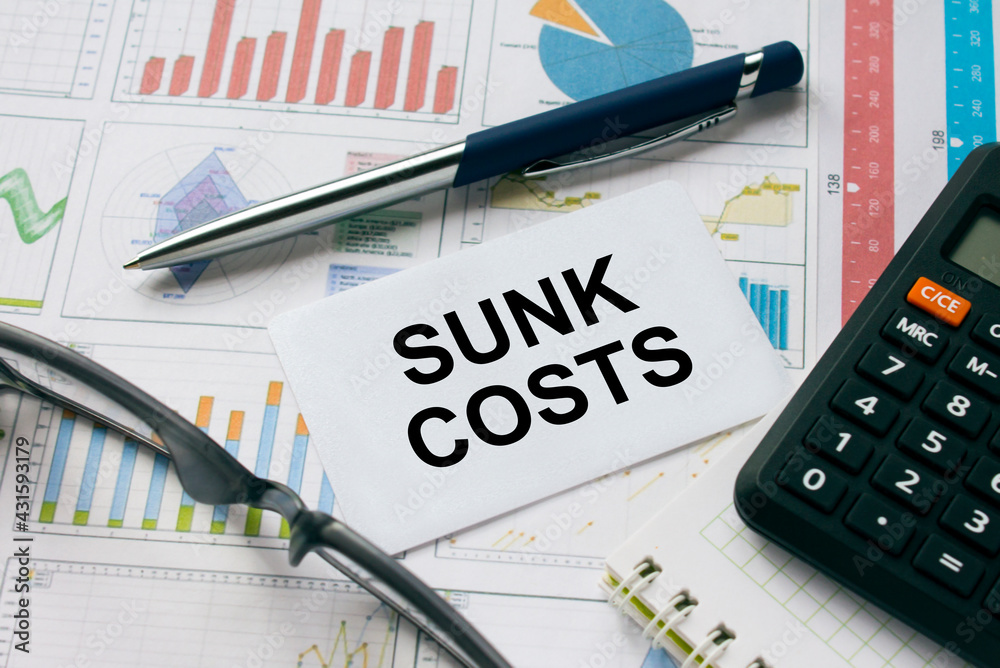 Business card with text Sunk Costs with, glasses, pen and calculator Business card with text Sunk Costs with, glasses, pen and calculator