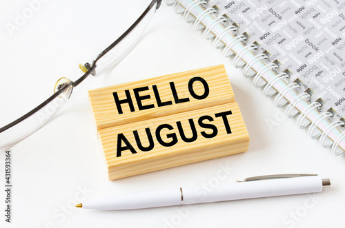 Text Hello August on a wooden blocks lying near notepad with eyeglasses and pen