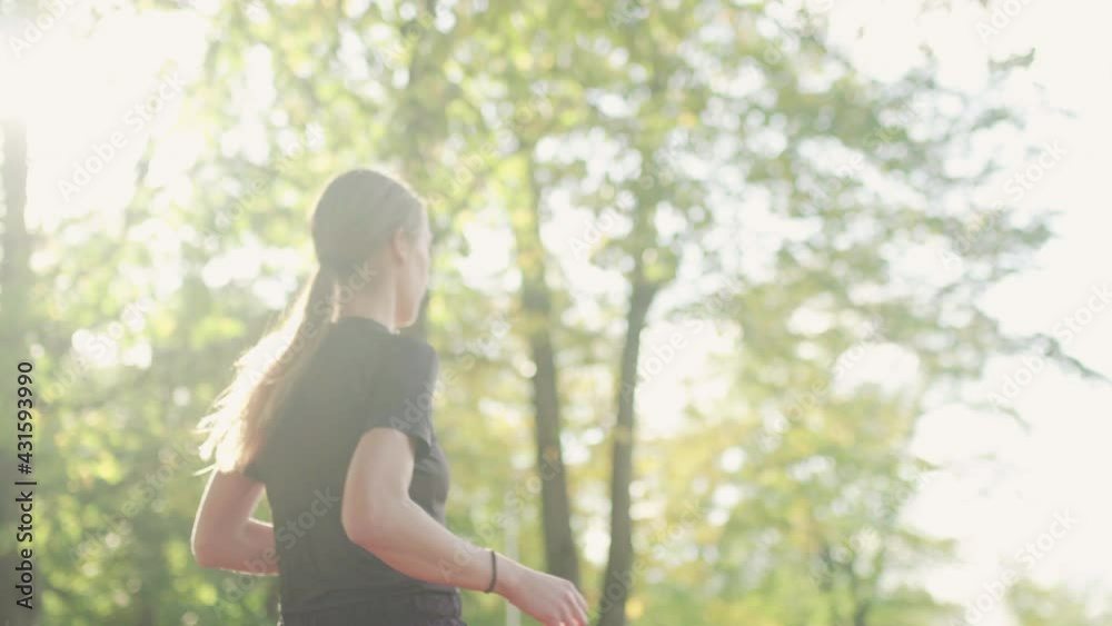 Fitness girl with ponytail running in the park. View from behind Fitness girl with ponytail running in the park. View from behind