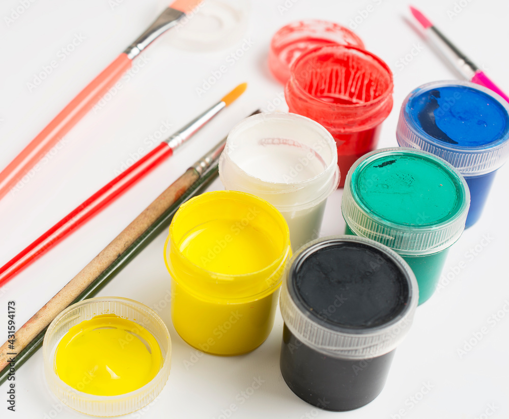jars with acrylic paint and small brushes on a white background. jars with acrylic paint and small brushes on a white background.