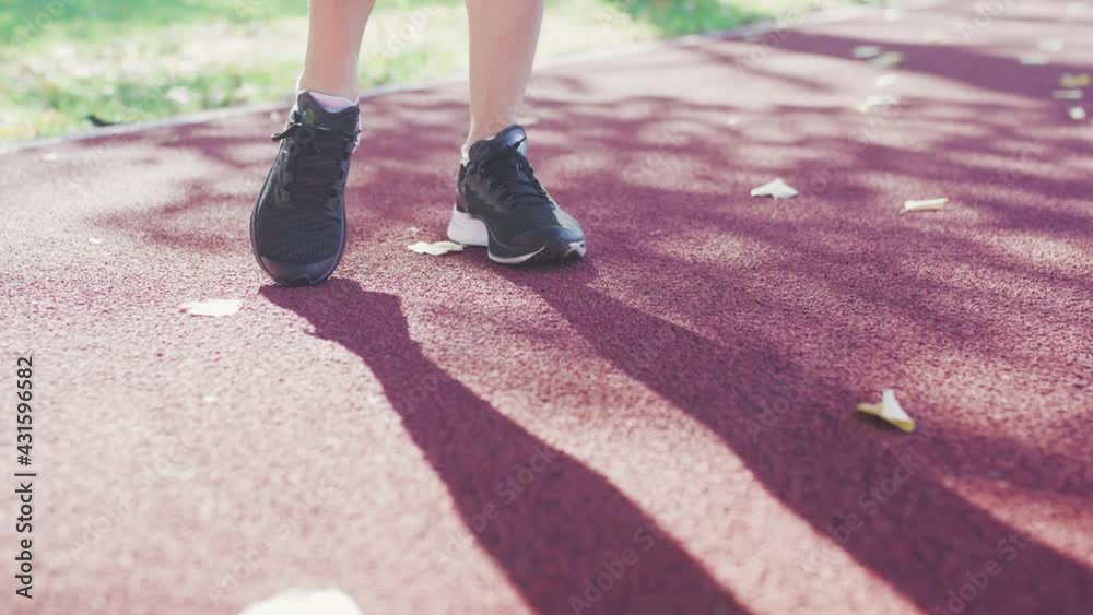 Runner girl stretching her feet on an all weather synthetic track surface in the park. Warming up exercise for running Runner girl stretching her feet on an all weather synthetic track surface in the park. Warming up exercise for running