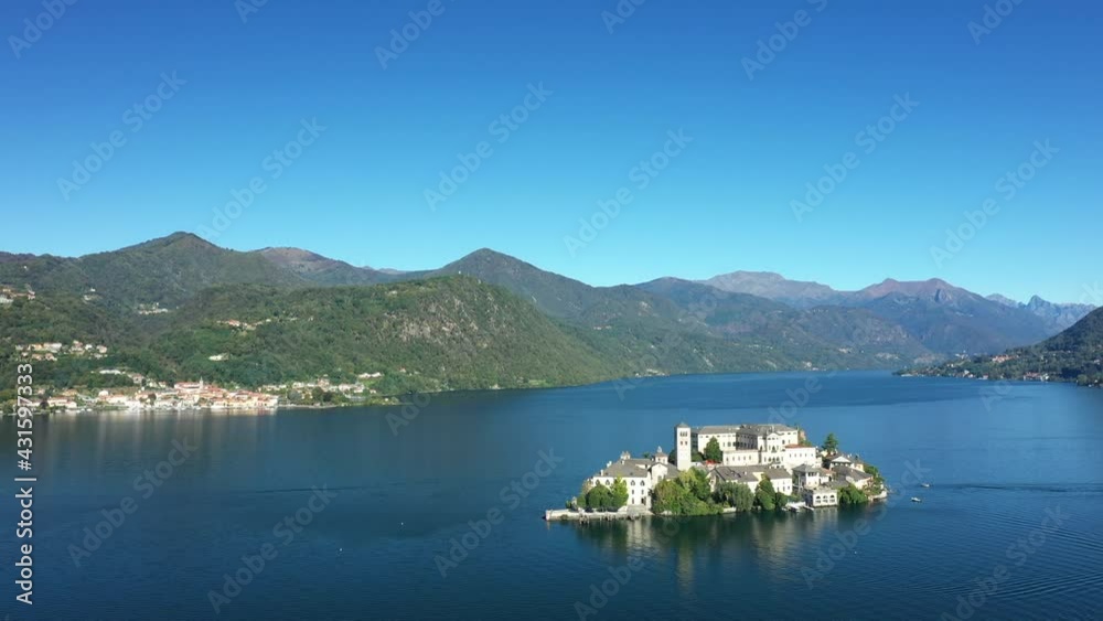 L'île Saint-Jules (Isola di San Giulio) au milieu du lac d'Orta dans le Piémont, vers les Alpes, en Italie, en drone, à l'automne lors d'une journée sous le Soleil.