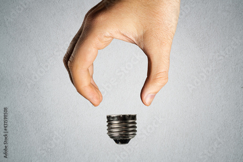 Man holding invisible bulb and visible socket on light background. Negative space