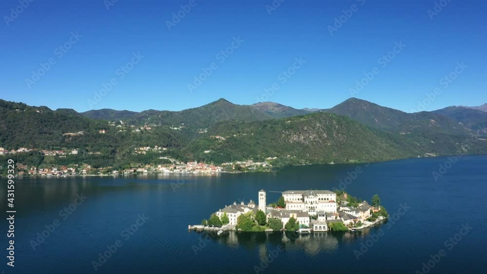 L'île Saint-Jules (Isola di San Giulio) au milieu du lac d'Orta dans le Piémont, vers les Alpes, en Italie, en drone, à l'automne lors d'une journée sous le Soleil.