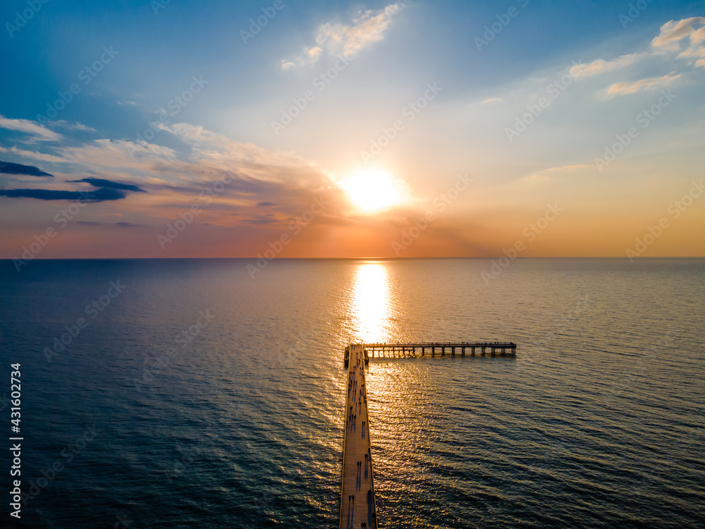 Aerial view of pedestrians bridge to the sea and a sunset in horizon