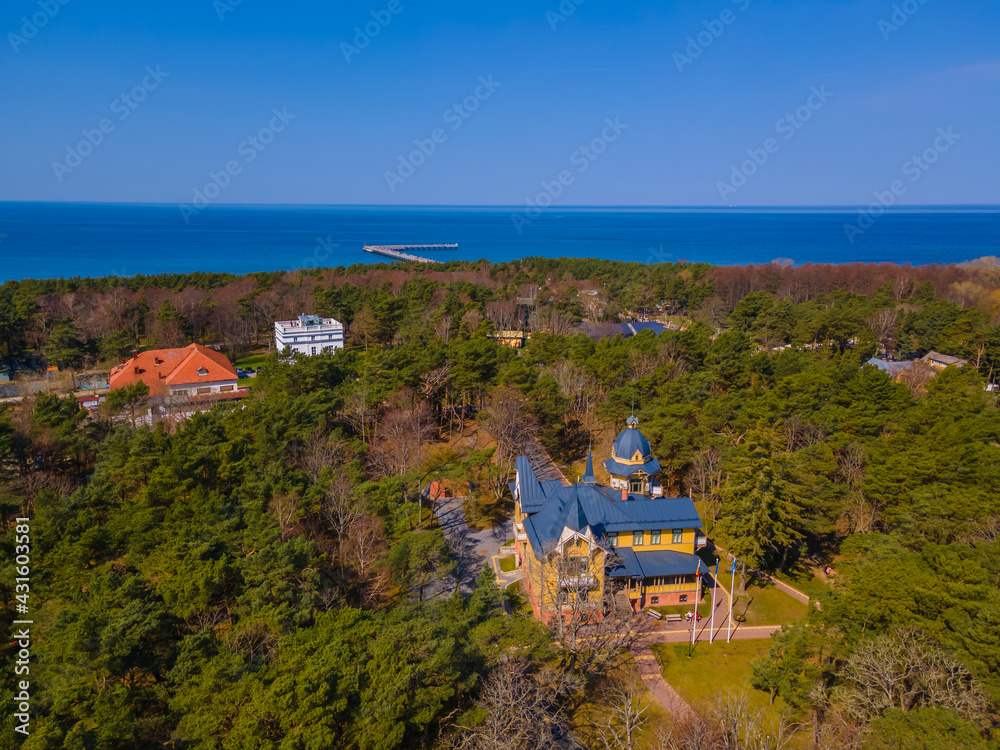 Aerial panoramic view of Palanga resort, Palanga city museum and other building among pines with a sea bridge in the distance in Baltic sea