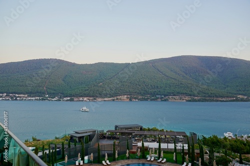 Coast of Turkey, Bodrum. Tourist yacht in beautiful emerald-blue sea. Blue sea water pools in the foreground, tropical nature. Landscape, view of Aegean Sea. Tourism (travel) to Bodrum Turkey