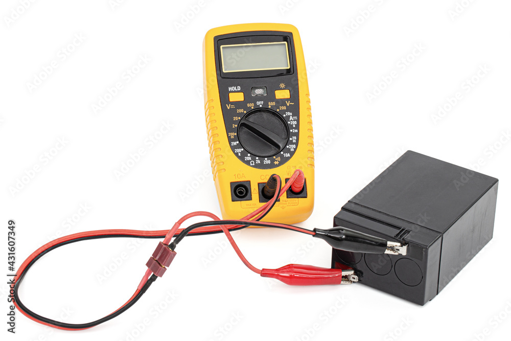 Testing an acid rechargeable battery with a measuring instrument isolated on white background Testing an acid rechargeable battery with a measuring instrument isolated on white background