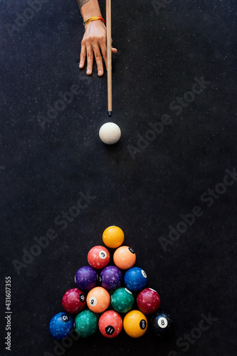 The hand of a man with a billiard cue aims at a billiard ball photo