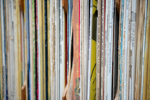 A bookshelf filled with multiple rows of record albums in their covers. The retro collection of nostalgia albums are from a radio station. The classical library of vinyl records are on four shelves.