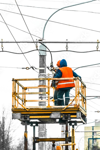 Two working men raised safety on a machine crane equipment mending a power electric line