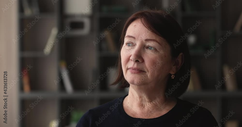 Head shot portrait of dreamy elderly Caucasian woman looking into distance. Older generation X citizen daydreaming, enjoy carefree calm retired life, deep in pleasant thoughts standing alone indoors