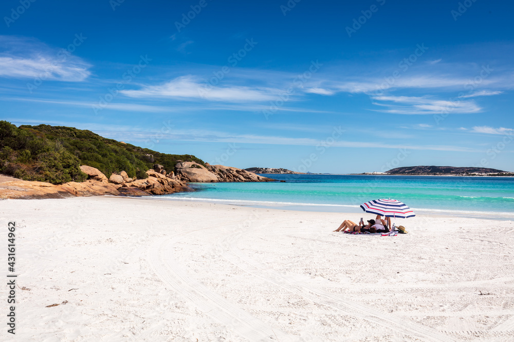 Holiday makers relax under an umbrella on the pristine white sand beach and sparkling waters of Wharton Bay in the Cape LeGrande National Park