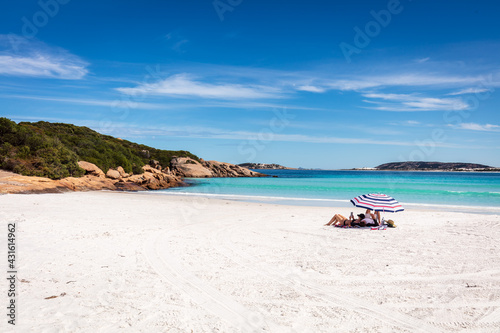 Holiday makers relax under an umbrella on the pristine white sand beach and sparkling waters of Wharton Bay in the Cape LeGrande National Park