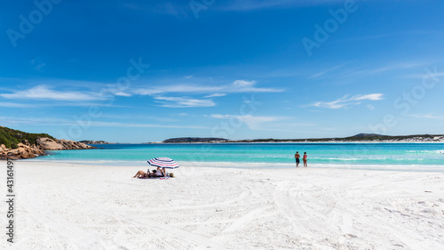 Fototapeta Naklejka Na Ścianę i Meble -  Holiday makers relax under an umbrella on the pristine white sand beach and sparkling waters of Wharton Bay in the Cape LeGrande National Park
