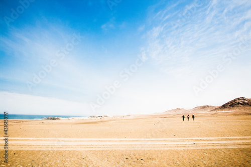 Gente caminando entre dunas en el desierto de Arequipa con cielo azul
