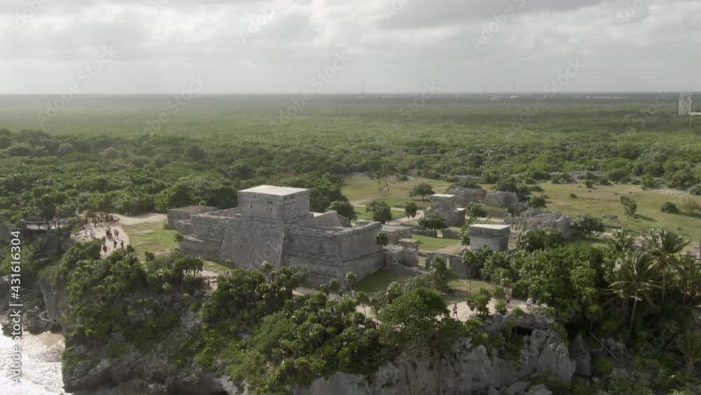Aerial Tilt Down Shot Of People Exploring Tulum Ruins On Sunny Day, Drone Flying Over Tourists At Famous Historic Landmark Against Cloudy Sky Aerial Tilt Down Shot Of People Exploring Tulum Ruins On Sunny Day, Drone Flying Over Tourists At Famous Historic Landmark Against Cloudy Sky