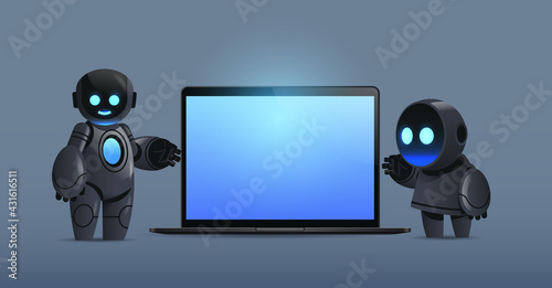 modern robots couple standing near laptop with blank screen robotic character artificial intelligence technology
