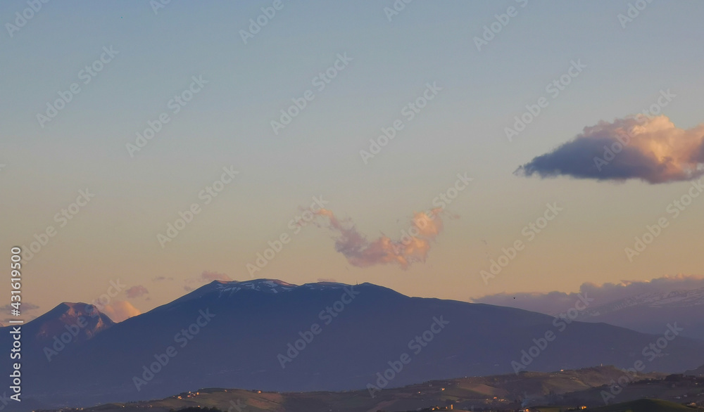 Montagne innevate dell’Appennino cielo azzurro nuvole e uccelli in volo al tramonto