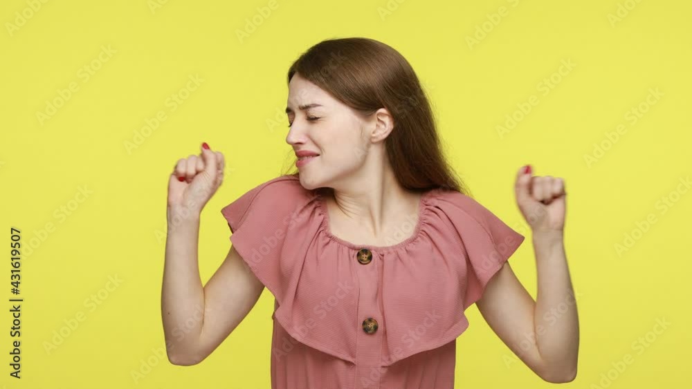 Tired exhausted curly haired woman with brown hair covers opened mouth and yawns wakes up very early to finish work, stands bored, wears pink dress. Indoor studio shot isolated on yellow background. Tired exhausted curly haired woman with brown hair covers opened mouth and yawns wakes up very early to finish work, stands bored, wears pink dress. Indoor studio shot isolated on yellow background.