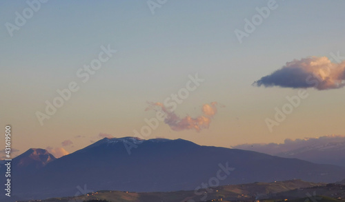 Montagne innevate dell   Appennino cielo azzurro nuvole e uccelli in volo al tramonto