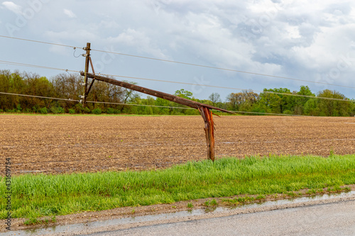 Broken electrical utility pole and power lines due to severe weather. Concept of storm damage, power outage, and electricity danger.