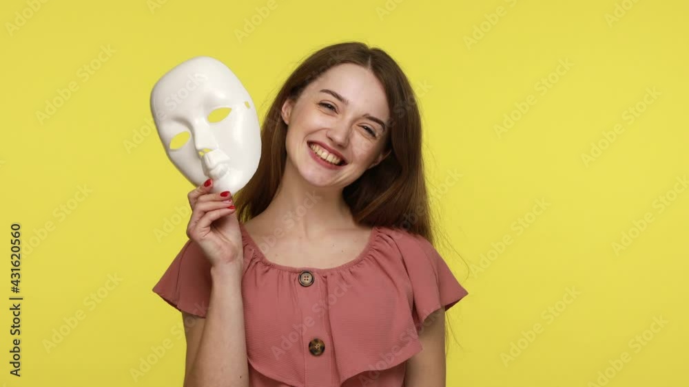 Multiple personality. Woman in summer dress showing different emotions, taking off mask changing facial expressions, happiness, sadness, amazement. Indoor studio shot isolated on yellow background. Multiple personality. Woman in summer dress showing different emotions, taking off mask changing facial expressions, happiness, sadness, amazement. Indoor studio shot isolated on yellow background.