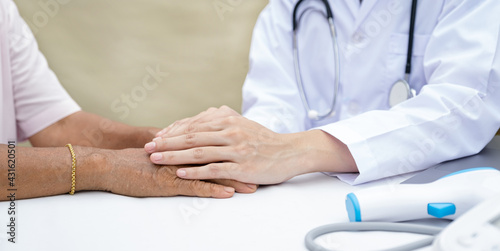 The doctor holding hands to encouragement and explained the health examination results to the elderly patient and guides friendly health care