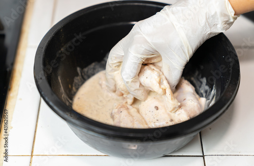 Cook marinate spieces and chicken in black bowl. photo