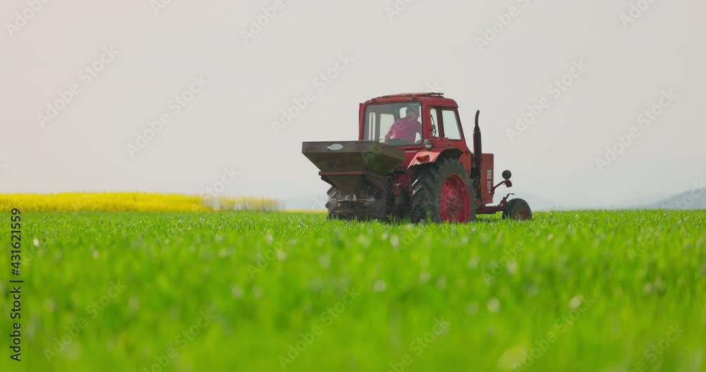 Tractor fertilizing in field. Farmer spraying with pesticides young plants on field Tractor fertilizing in field. Farmer spraying with pesticides young plants on field