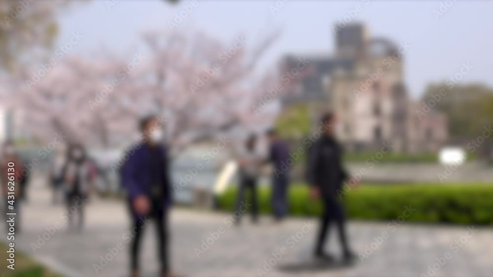 Blurred shot of tourists with mask walking in Hiroshima Peace Memorial Park, Japan. 4K. People traveling in Hiroshima. Blurred shot of tourists with mask walking in Hiroshima Peace Memorial Park, Japan. 4K. People traveling in Hiroshima.