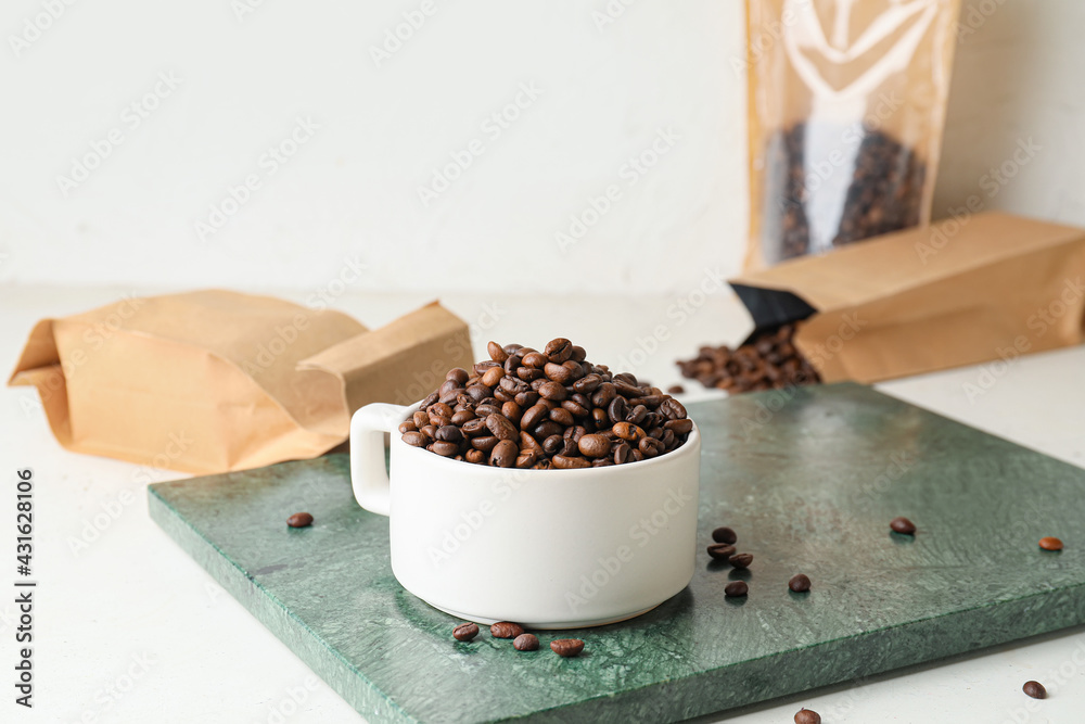 Cup with coffee beans on light background - obrazy, fototapety, plakaty 