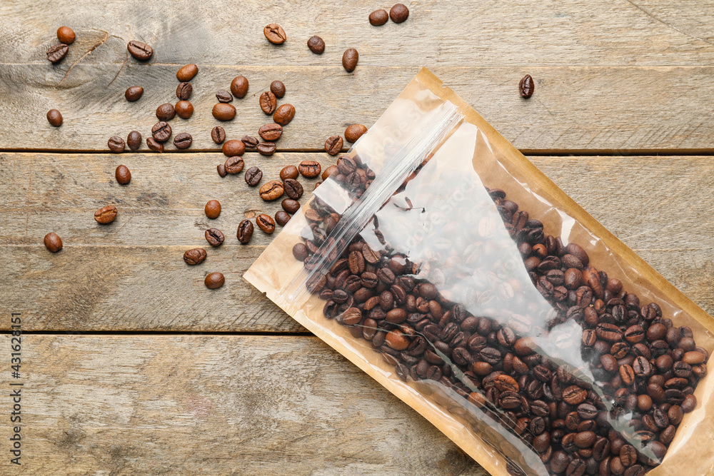 Bag with coffee beans on wooden background - obrazy, fototapety, plakaty 